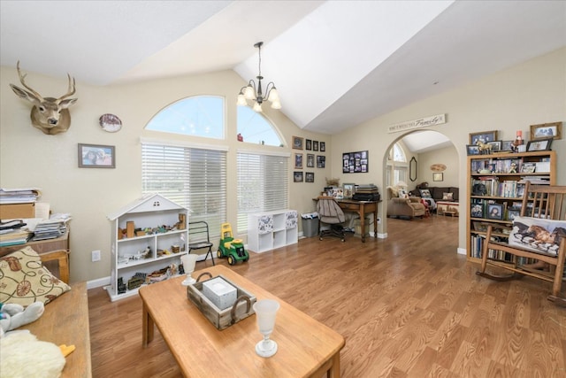 living area with lofted ceiling, an inviting chandelier, wood finished floors, arched walkways, and baseboards