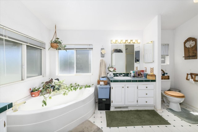 bathroom featuring a bath, toilet, vanity, and tile patterned floors
