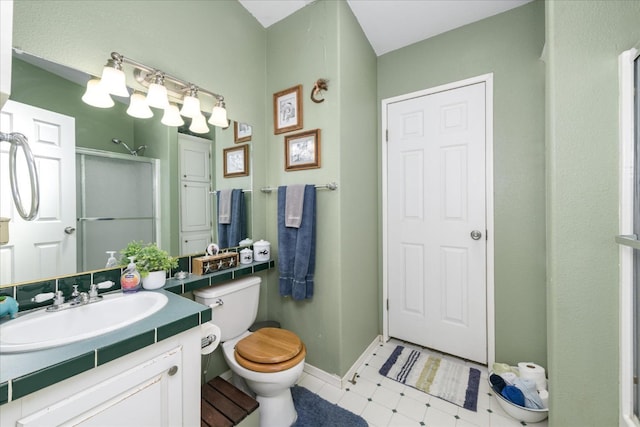 bathroom with tile patterned floors, toilet, vanity, baseboards, and a stall shower