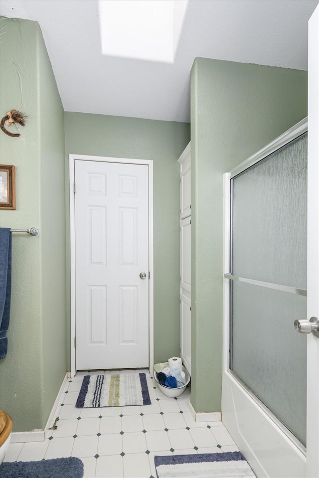 full bathroom with combined bath / shower with glass door, tile patterned floors, baseboards, and toilet