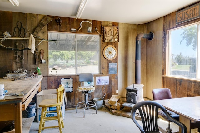 interior space featuring concrete flooring, a wood stove, wooden walls, and a wealth of natural light