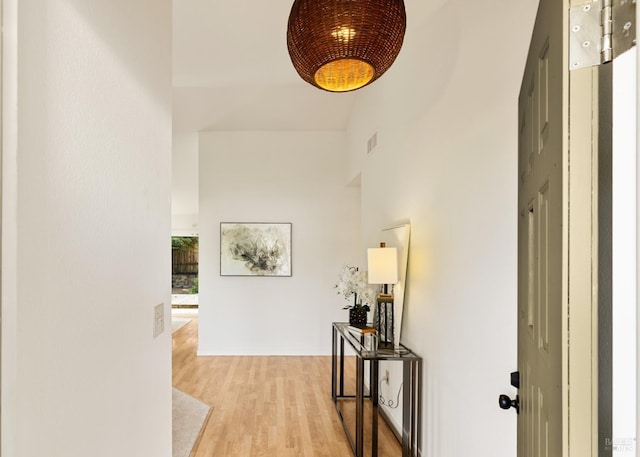 corridor featuring a towering ceiling, wood finished floors, and visible vents
