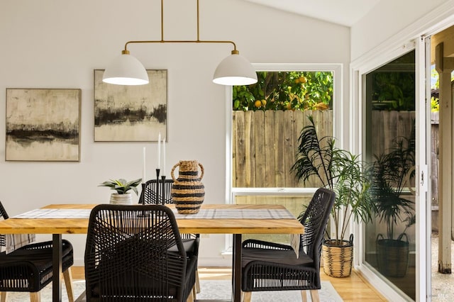 dining room with vaulted ceiling, a healthy amount of sunlight, and light wood-type flooring