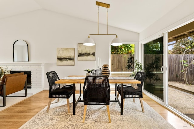 dining space featuring a fireplace, lofted ceiling, and wood finished floors