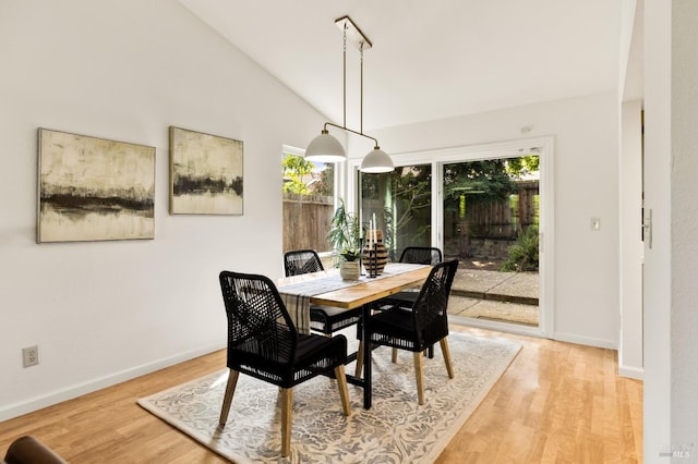 dining room featuring vaulted ceiling, baseboards, and a healthy amount of sunlight