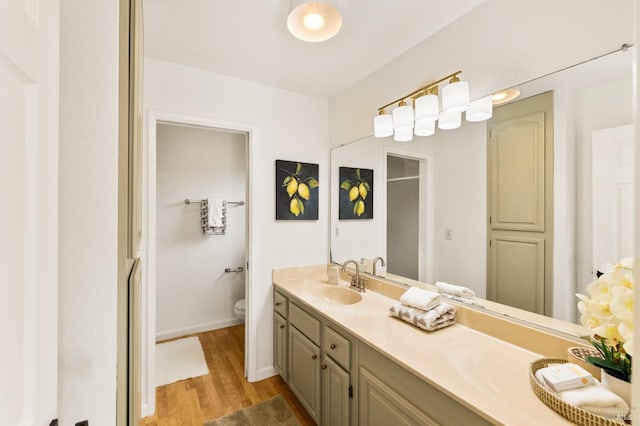 full bath featuring baseboards, wood finished floors, vanity, and toilet