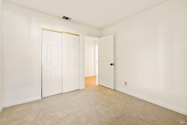 unfurnished bedroom featuring baseboards, visible vents, carpet, and a closet