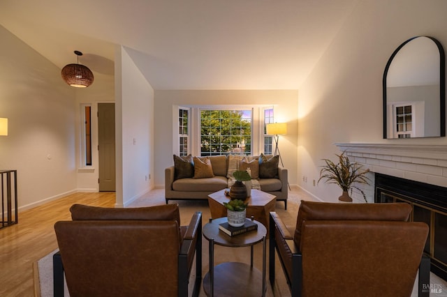 living room featuring a fireplace, vaulted ceiling, wood finished floors, and baseboards