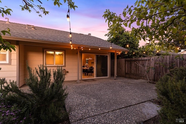 back of house featuring fence, a patio area, and a shingled roof