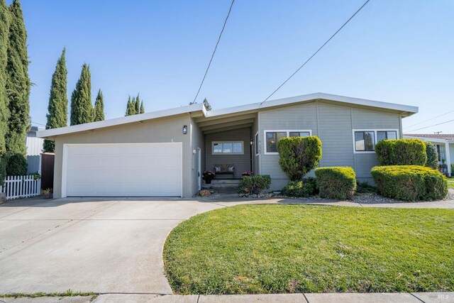 single story home featuring concrete driveway, a front lawn, fence, and a garage