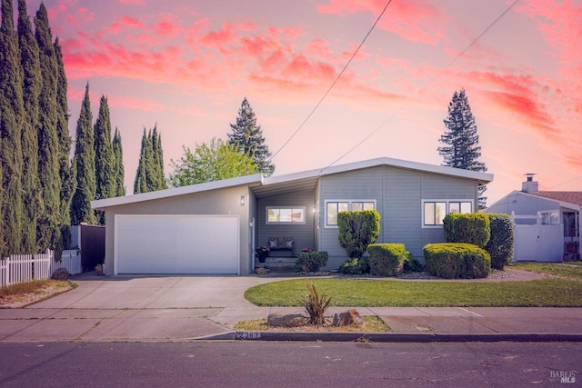 single story home with an attached garage, a front yard, fence, and driveway
