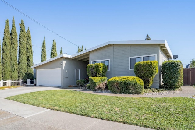 ranch-style home featuring fence, an attached garage, driveway, and a front lawn
