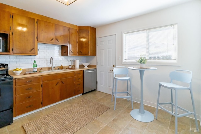 kitchen featuring brown cabinets, stainless steel dishwasher, a sink, black electric range, and tasteful backsplash