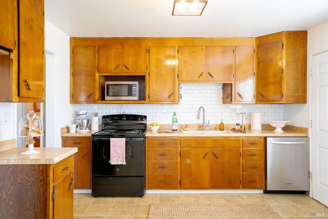 kitchen featuring stainless steel appliances, light countertops, a sink, and tasteful backsplash