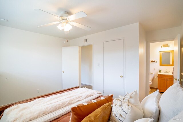 bedroom with visible vents, a ceiling fan, a sink, ensuite bath, and a closet