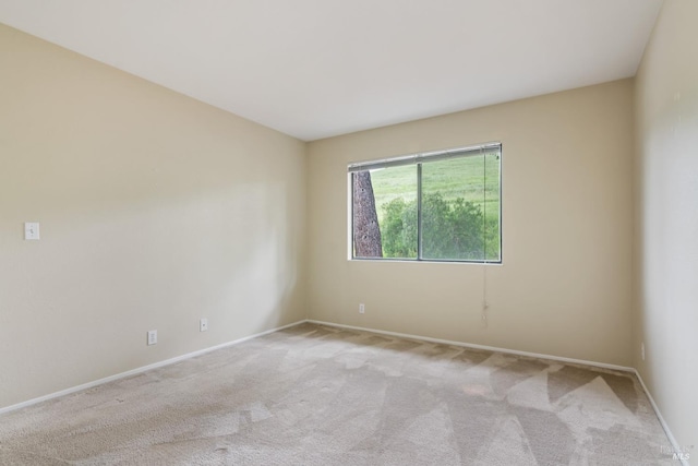 empty room featuring baseboards and light colored carpet
