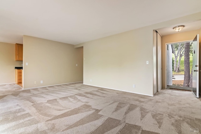 spare room with light carpet and baseboards