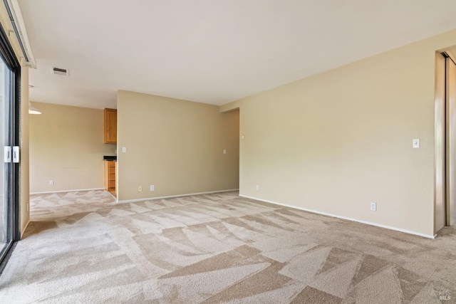 spare room featuring light colored carpet, baseboards, and visible vents