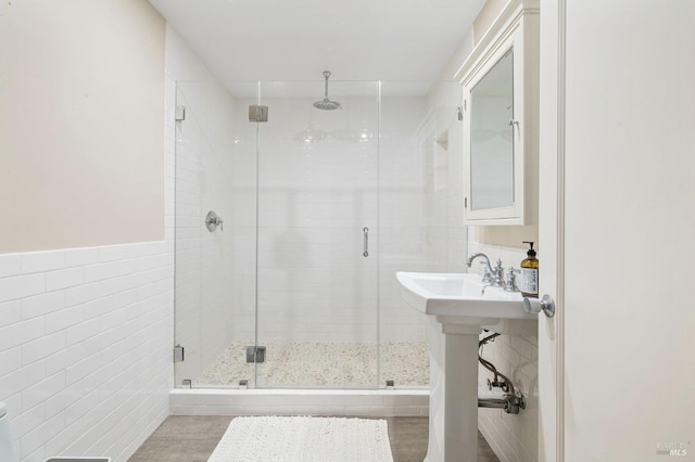 bathroom featuring tile walls, a stall shower, and a sink