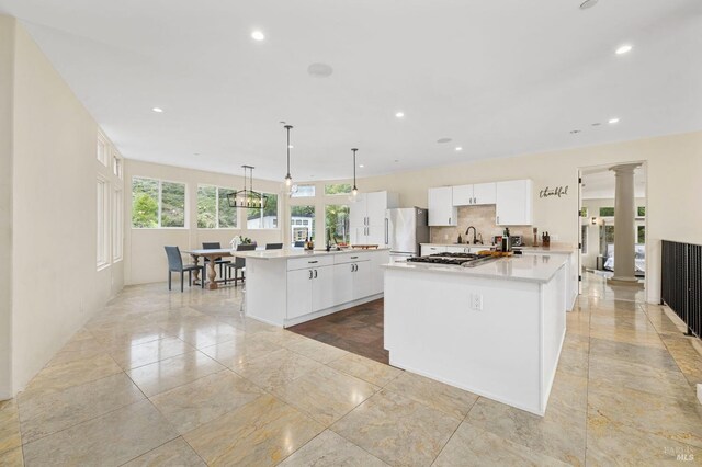 kitchen featuring ornate columns, white cabinets, recessed lighting, light countertops, and decorative backsplash