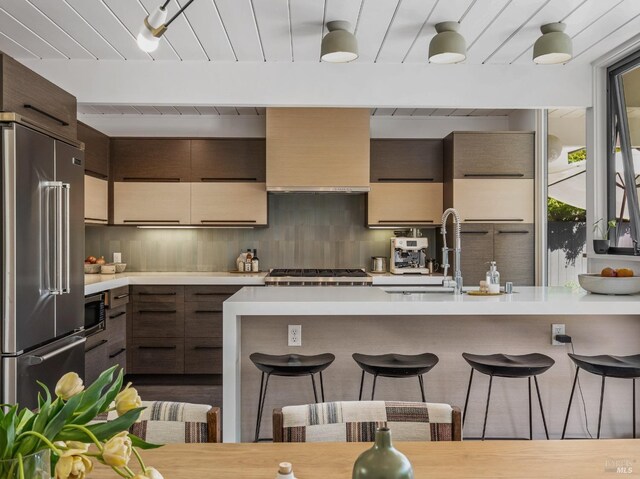 kitchen with backsplash, appliances with stainless steel finishes, a breakfast bar, and light countertops