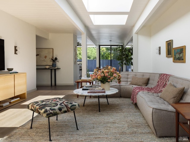 living room with a skylight, baseboards, wood finished floors, and floor to ceiling windows