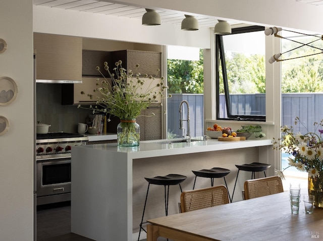 kitchen with light countertops, luxury stove, a sink, and a kitchen bar
