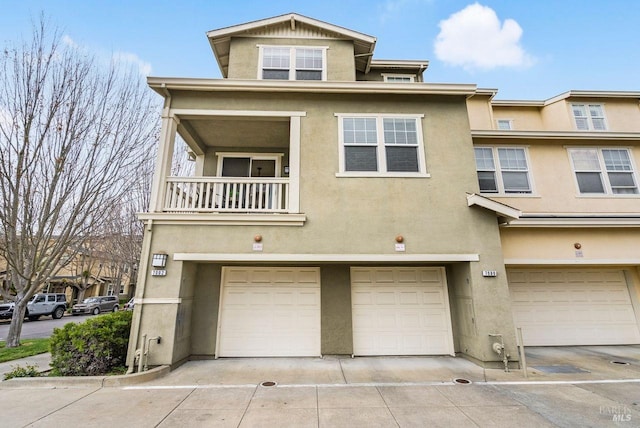 townhome / multi-family property featuring a garage, stucco siding, a balcony, and concrete driveway
