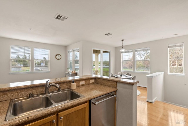 kitchen with brown cabinets, a sink, dishwasher, visible vents, and pendant lighting