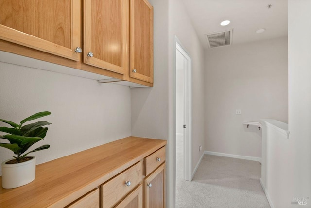 laundry area featuring baseboards, light colored carpet, and visible vents