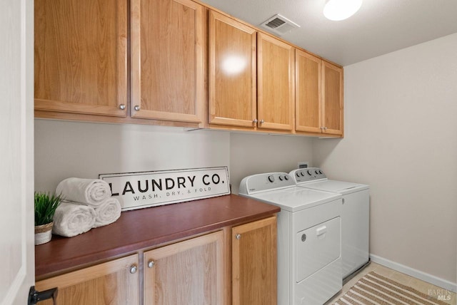 laundry area with visible vents, baseboards, washing machine and clothes dryer, cabinet space, and light tile patterned floors