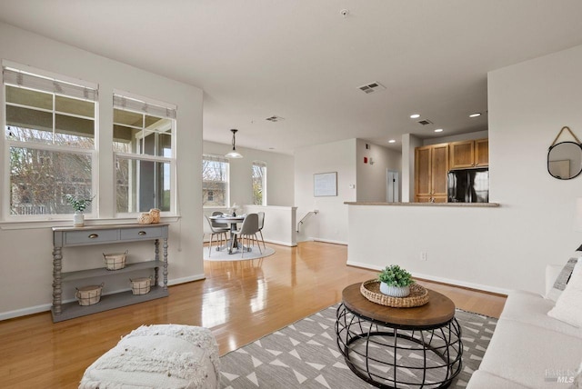living area featuring visible vents, recessed lighting, light wood-style floors, and baseboards