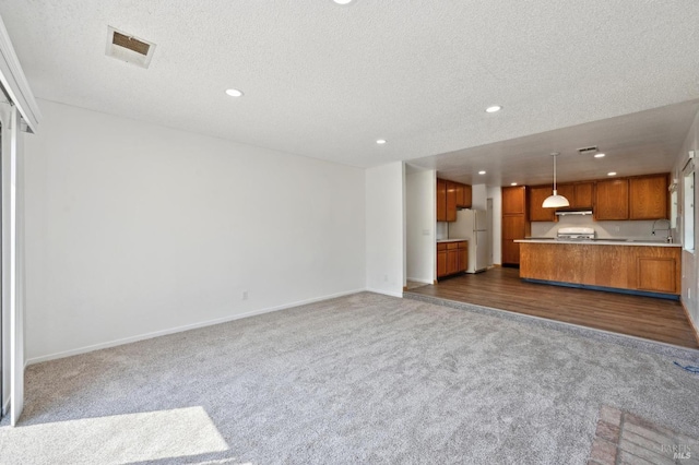 unfurnished living room with baseboards, dark colored carpet, a sink, and recessed lighting