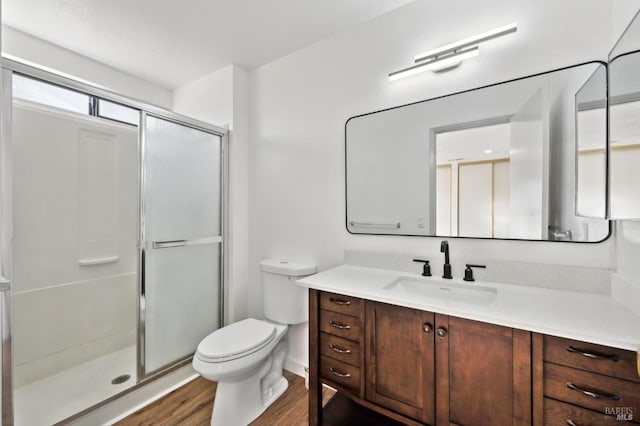 full bathroom with toilet, a healthy amount of sunlight, a stall shower, wood finished floors, and vanity