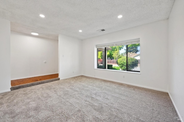 carpeted spare room with baseboards, visible vents, recessed lighting, and a textured ceiling