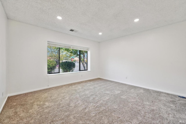 carpeted spare room featuring recessed lighting, a textured ceiling, visible vents, and baseboards
