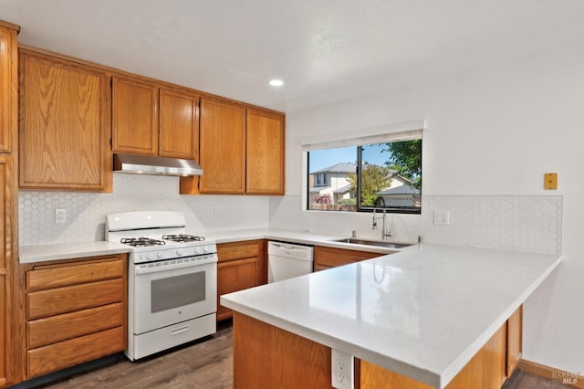 kitchen featuring a peninsula, a sink, white appliances, light countertops, and under cabinet range hood
