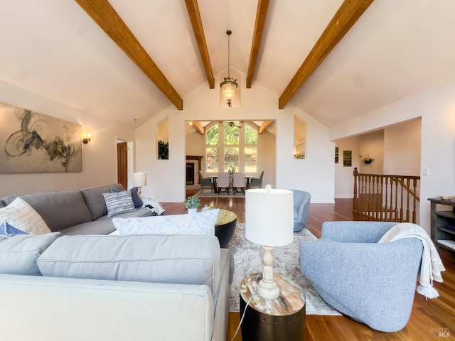 living area featuring a ceiling fan, vaulted ceiling with beams, and wood finished floors