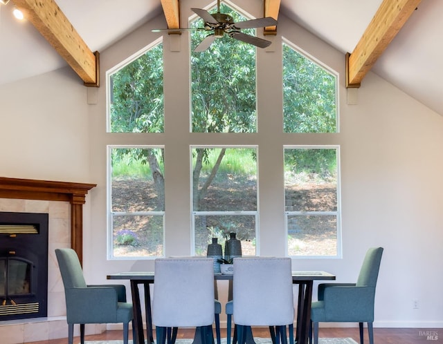 dining room with ceiling fan, a fireplace, beam ceiling, and high vaulted ceiling