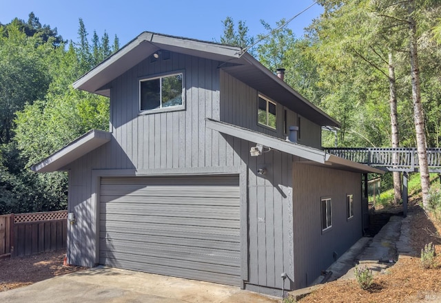 view of property exterior with concrete driveway, fence, and a garage