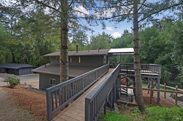 rear view of property featuring a wooden deck, stairs, roof with shingles, and a garage