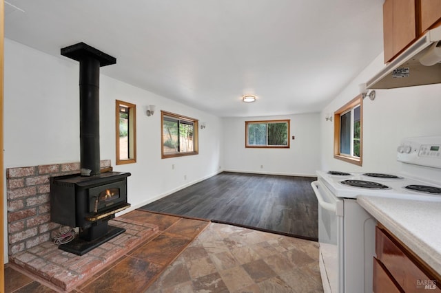 unfurnished living room with baseboards, a wood stove, and stone finish flooring