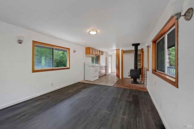 unfurnished living room with baseboards, dark wood-style floors, and a wood stove