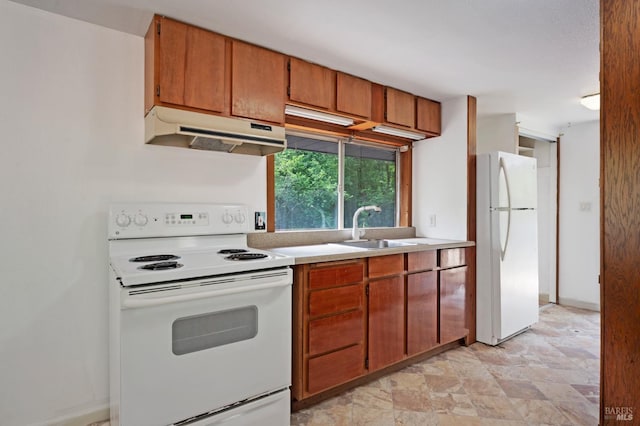 kitchen with stone finish floor, under cabinet range hood, white appliances, a sink, and light countertops