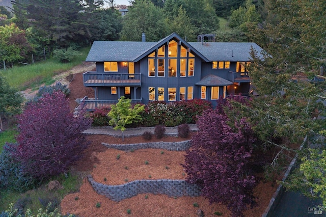 rear view of house with a balcony and roof with shingles