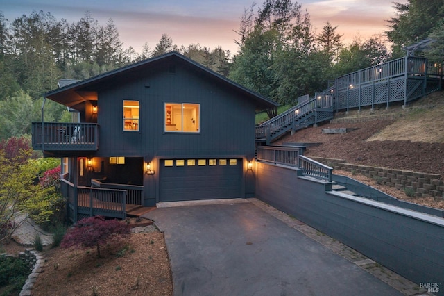 view of front of property with stairway, a deck, an attached garage, and aphalt driveway