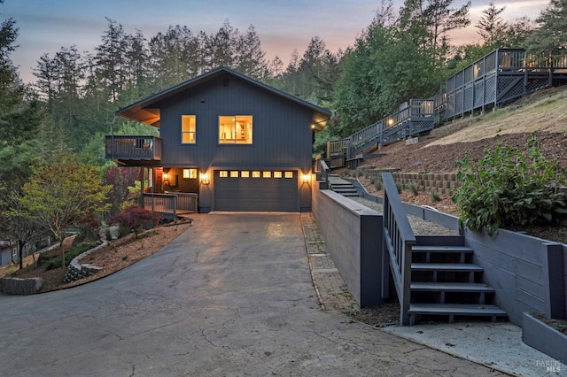 view of front facade featuring a balcony, stairs, an attached garage, and aphalt driveway