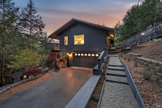 rustic home featuring stairway, an attached garage, and driveway