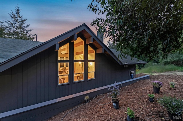 property exterior at dusk with roof with shingles