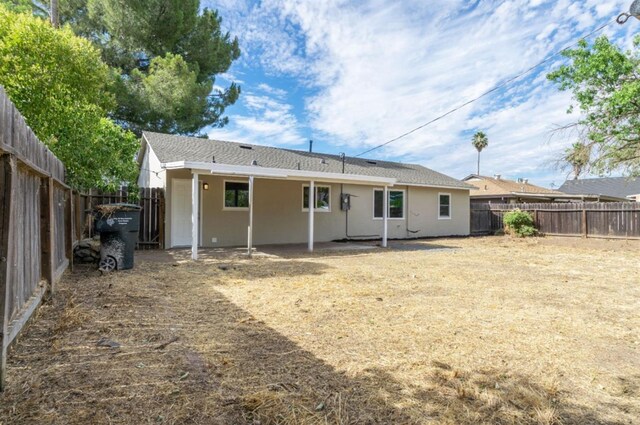 rear view of house with a fenced backyard and stucco siding